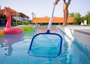 A person using a pool skimmer